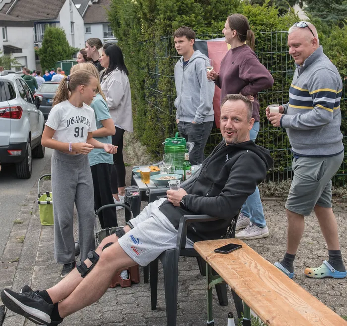 Menschen bei einer Zusammenkunft des Schützenvereins Kierspe, darunter ein sitzender, lächelnder Mann und mehrere stehende Personen.