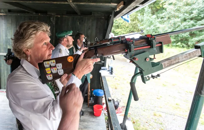 Eine Frau zielt mit einem auf einem grünen Gestell montierten Gewehr beim Schützenfest.