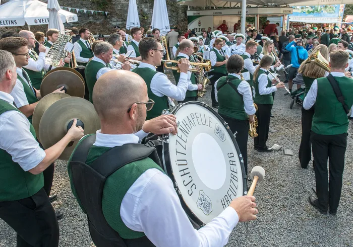 Blaskapelle in grünen Westen spielt Instrumente bei einem Schützenfest, im Vordergrund eine große Trommel mit der Aufschrift „Schützenkapelle Kreuzberg“.