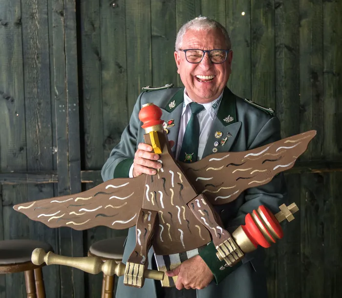 Hugo Mimm lächelt in seiner grünen Schützenuniform und hält eine große hölzerne Vogelfigur.