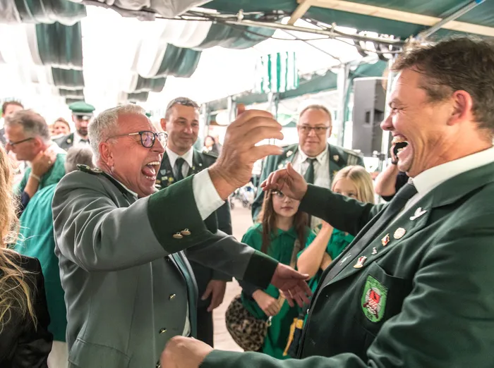 Zwei Männer in grünen Uniformen lachen unter einem Festzelt beim Schützenfest des ASV Kierspe.