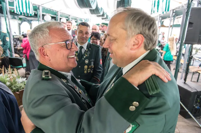 Zwei Männer in grünen Uniformen umarmen sich lächelnd beim Schützenfest des ASV Kierspe.