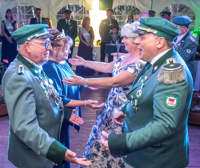 Personen in grünen Uniformen mit Orden und festlich gekleidete Gäste bei einer feierlichen Begegnung während des Schützenfestes.