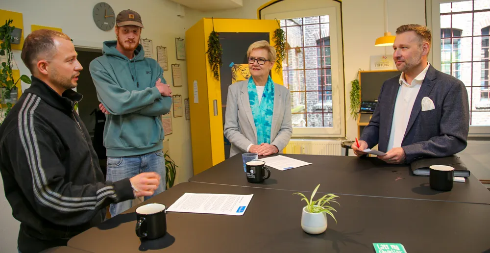 Vier Personen sitzen oder stehen um einen großen Tisch und diskutieren. Von links: Alex Breuker, Björn Hafke, Eva Kirchhoff und Stephan Masch.
