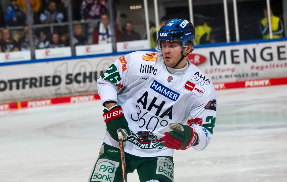 Eishockeyspieler Alexander Blank in voller Ausrüstung auf dem Eis, Trikot mit Sponsorenlogos und Nummer 26.