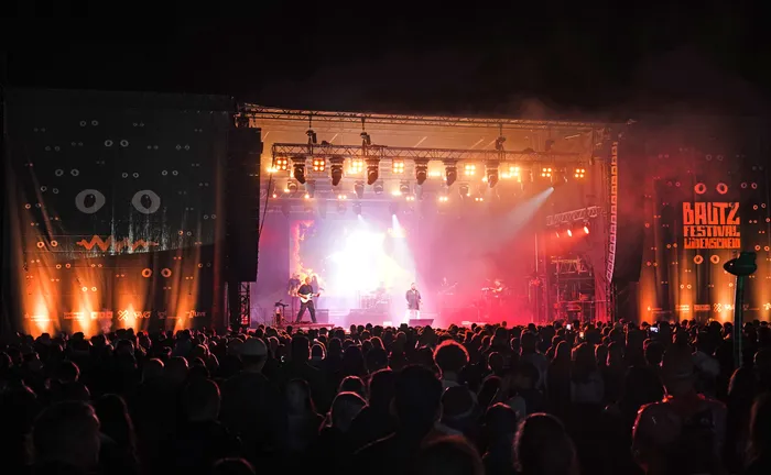 Die Band Alphaville tritt auf einer hell erleuchteten Bühne beim Baltz Festival vor einer großen Menschenmenge auf.