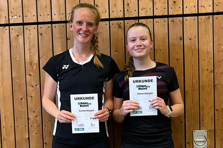 Zwei Badmintonspielerinnen halten Urkunden für das Damendoppel des 25HagenMasters in der Hand.
