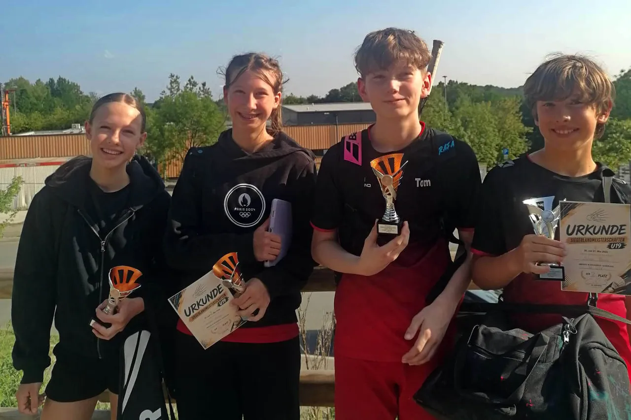 Vier junge Sportler*innen stehen mit Pokalen und Urkunden vor einer Sportanlage. Emilia und Sophie Baron, Tom Biehsmann und Julian Baron gewannen bei den Siegerlandmeisterschaften in Wenden.