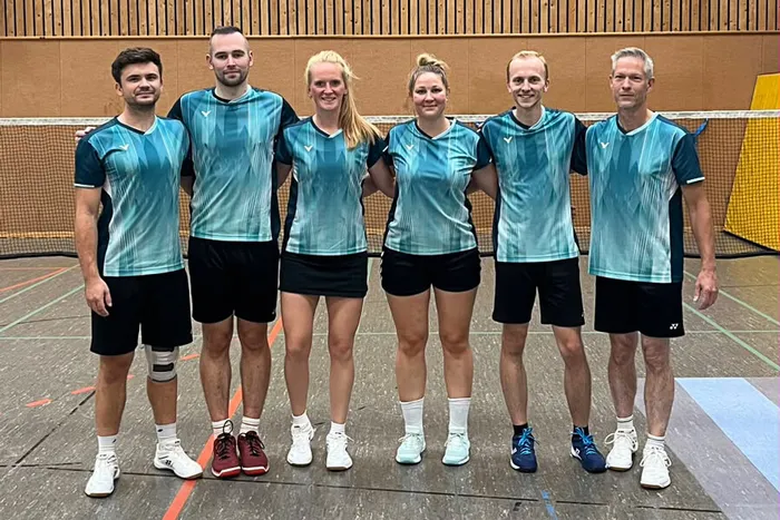 Sechs Mitglieder der ersten Mannschaft des BC Herscheid in einheitlichen blau-türkisen Trikots stehen in einer Sporthalle.