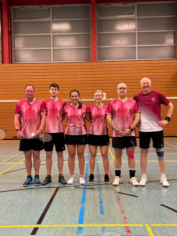 Sechs Mitglieder der zweiten Mannschaft des BC Herscheid in pinkfarbener Sportkleidung posieren in einer Sporthalle.