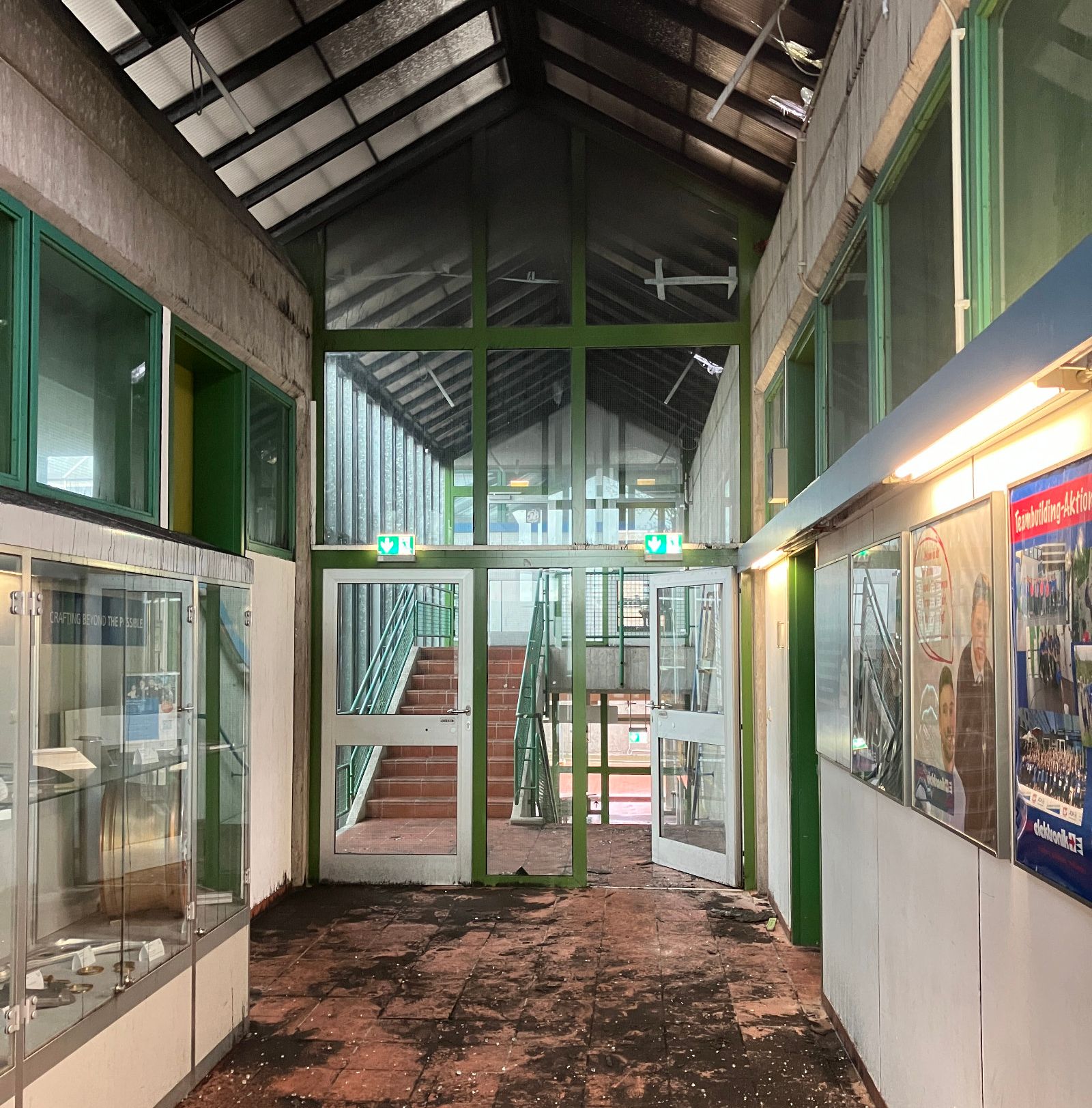 Ein Flur im Berufskolleg für Technik zeigt Wasserschäden an Wänden und Boden nach einem Brand während Dacharbeiten.