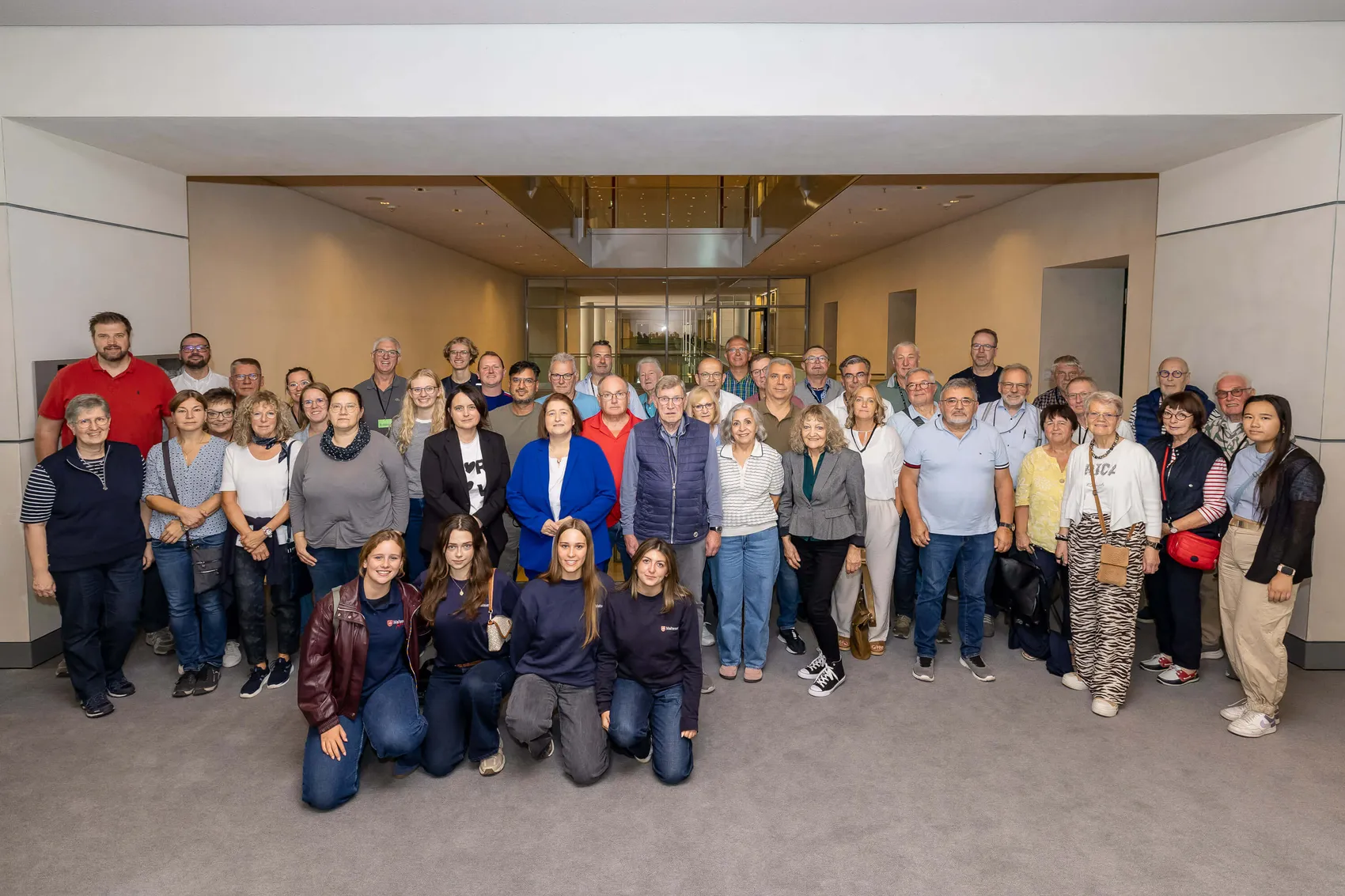 Eine Gruppe von etwa 50 Personen aus dem Märkischen Kreis posiert für ein gemeinsames Foto in einem Innenraum in Berlin.