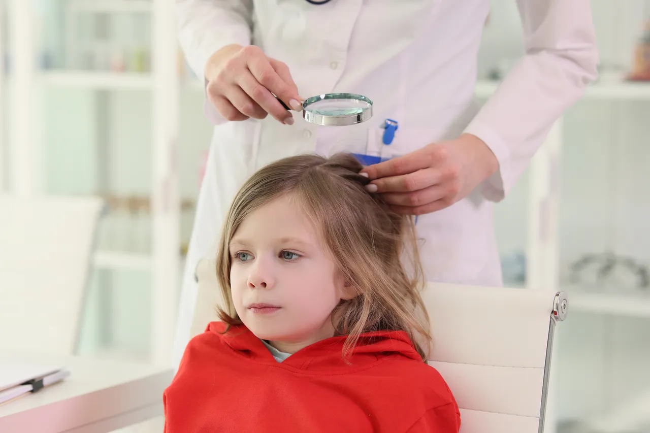 Eine Ärztin untersucht mit einer Lupe die Haare eines kleinen Mädchens. Das Mädchen trägt einen roten Pullover und sitzt auf einem Stuhl.
