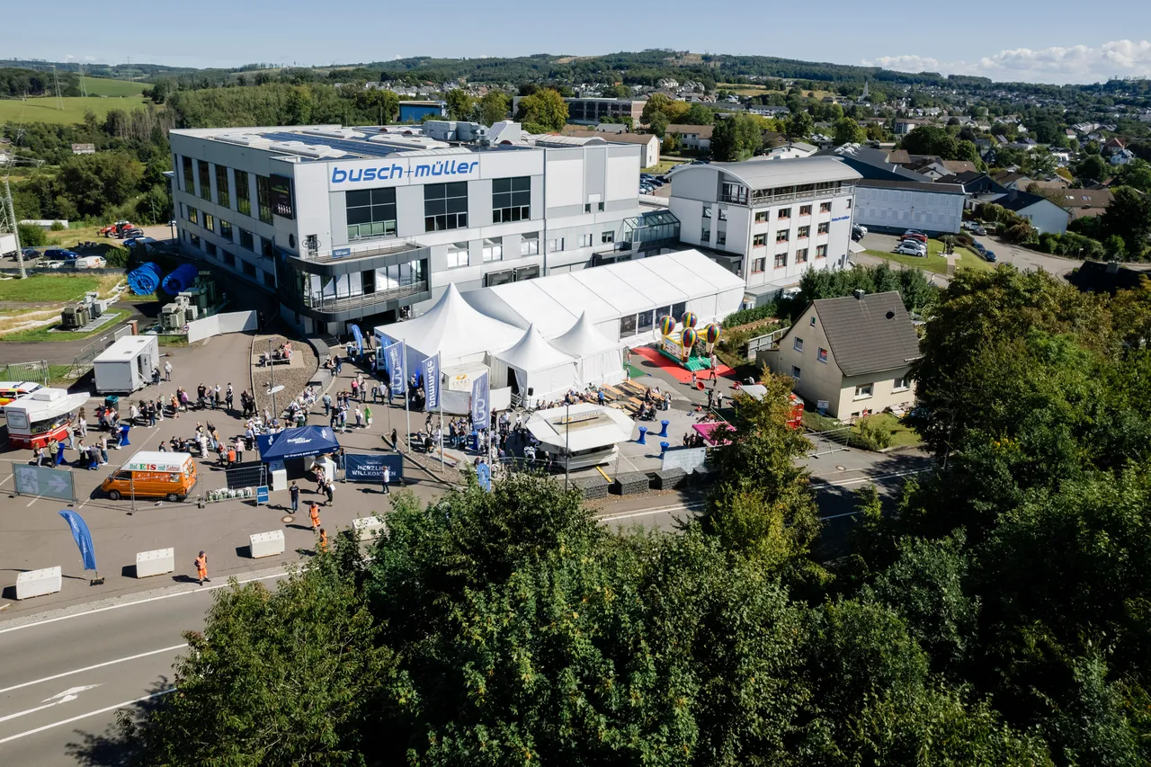 Luftaufnahme des Firmengeländes von Busch + Müller anlässlich des 100-jährigen Jubiläums mit Besuchern, Zelten und Fahrzeugen.