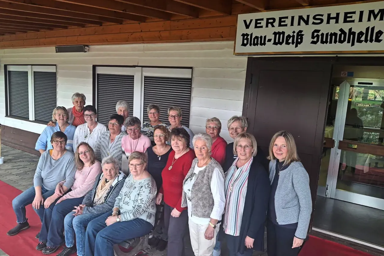 Gruppe von etwa zwanzig Frauen unterschiedlichen Alters posiert vor dem Schützenheim „Blau-Weiß Sundhelle“. Die amtierende Schützenkönigin sitzt in der ersten Reihe.