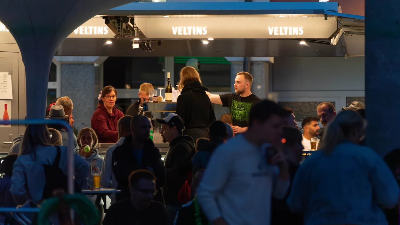 Getränkewagen mit dem Schriftzug „VELTINS“ auf einem Stadtfest, umgeben von Besuchern.