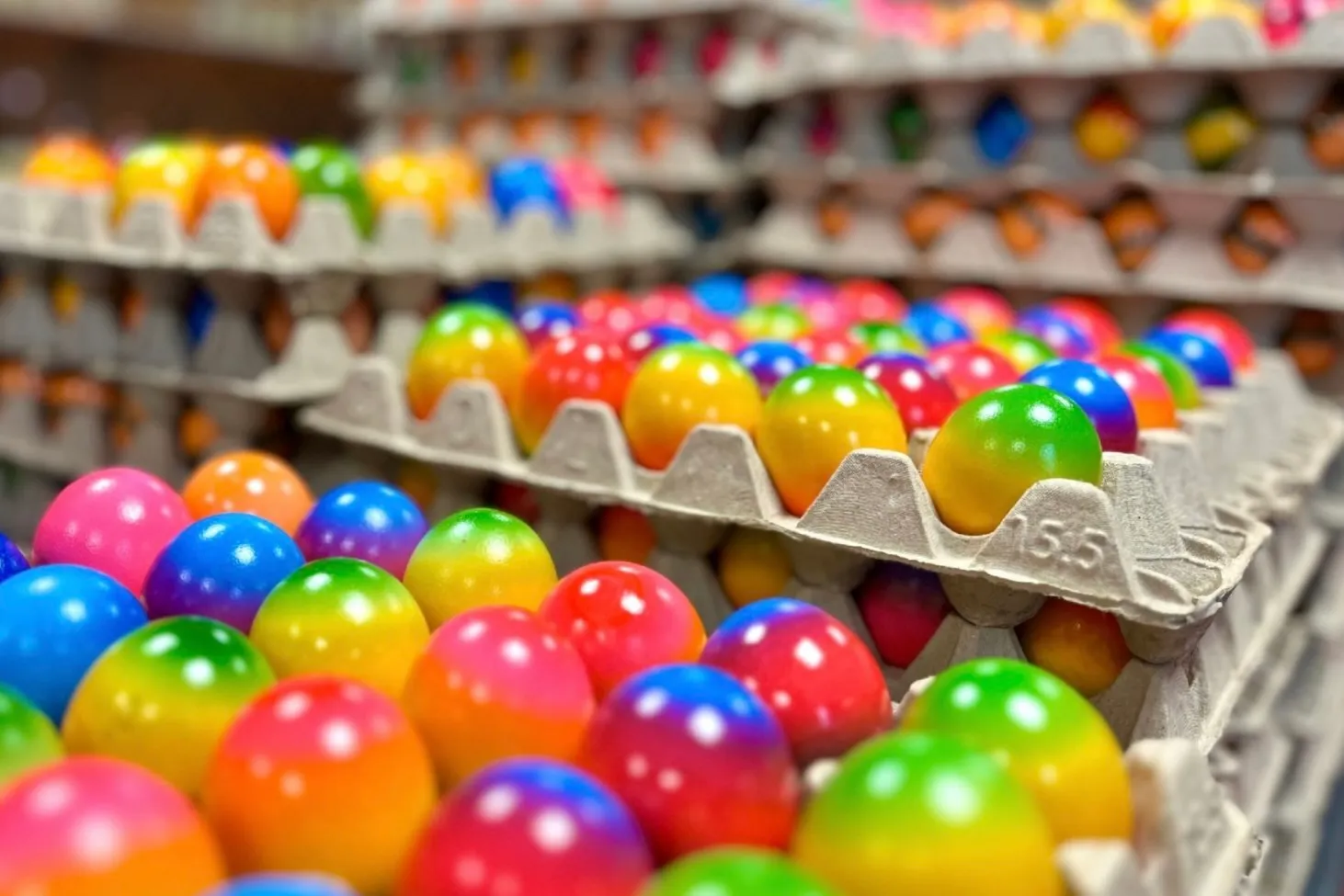 Mehrere Schalen mit bunten Plastikeiern in verschiedenen Farben, darunter Pink, Blau, Grün, Gelb und Orange, stehen bereit für die Osternzeit.