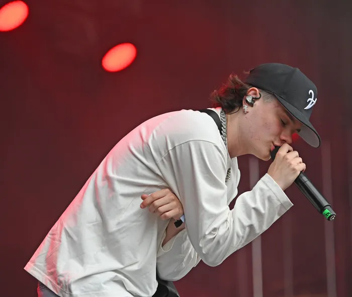 Benno singt mit einem Mikrofon auf der Mainstage vor einem roten, beleuchteten Hintergrund.