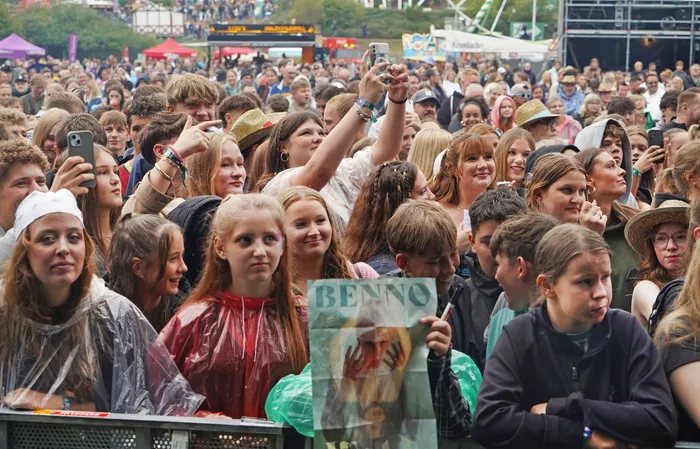 Eine dichte Menschenmenge bei einem Musikfestival, eine Person hält ein Poster mit der Aufschrift „BENNO“ hoch.