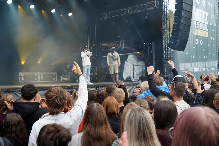 Benno performt auf der beleuchteten Mainstage des Baltz Festivals vor einer Menschenmenge mit erhobenen Händen.