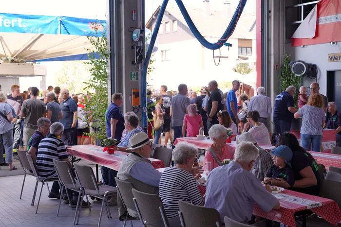 Viele Menschen sitzen an Tischen mit rot-weiß karierten Decken beim Bergfest der Löschgruppe Rärin.