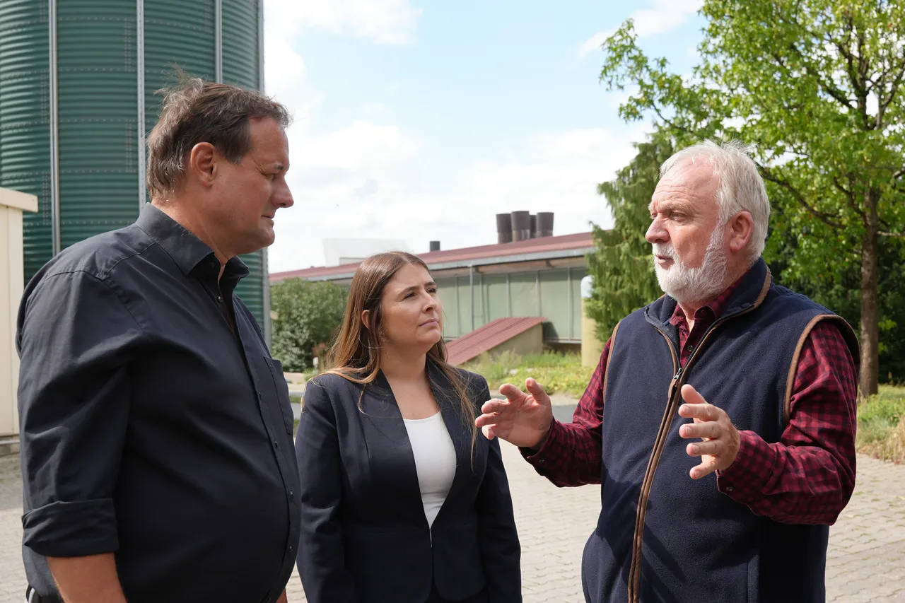 Thorsten Schick, Tijen Ataoğlu und Udo Baumeister im Gespräch vor einem grünen Silo und einem Gebäude.
