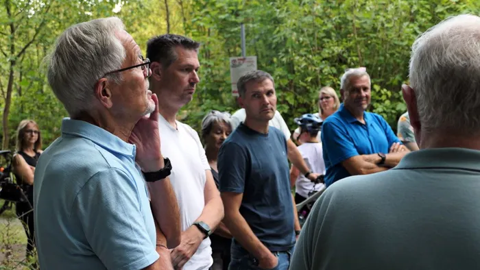 Eine Gruppe von Menschen steht bei einem Treffen im Waldgebiet des Grünetals.