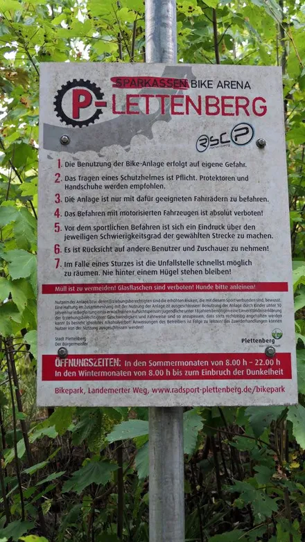 Hinweisschild der Sparkassen Bike Arena Plettenberg mit Verhaltensregeln, Öffnungszeiten und Informationen zur Nutzung des Bikeparks.