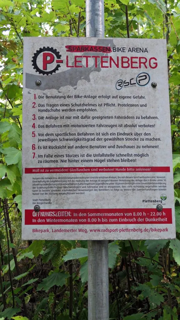 Hinweisschild der Sparkassen Bike Arena Plettenberg mit Verhaltensregeln, Öffnungszeiten und Informationen zur Nutzung des Bikeparks.