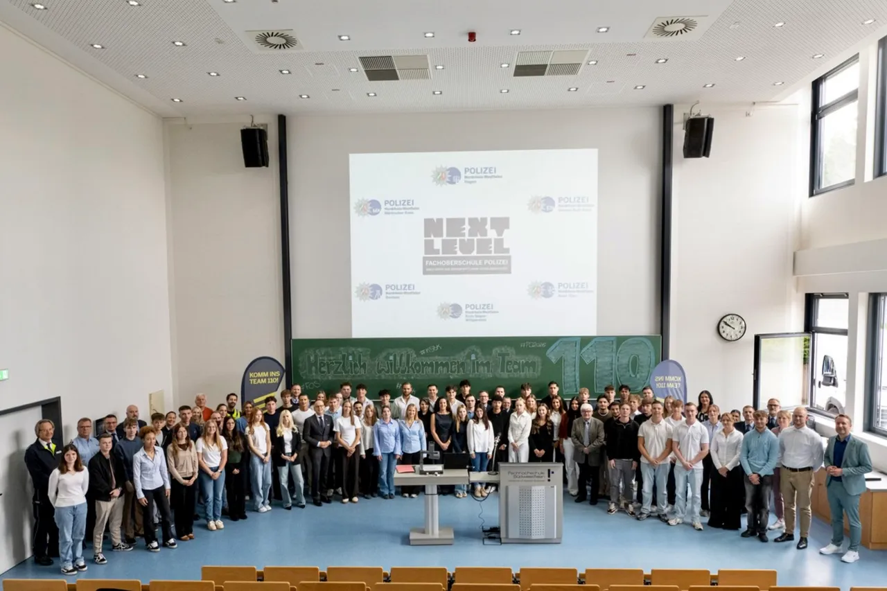 Eine große Gruppe von Menschen posiert für ein Gruppenfoto in einem Hörsaal vor einer Leinwand mit dem Schriftzug „POLIZEI NEXT LEVEL“.