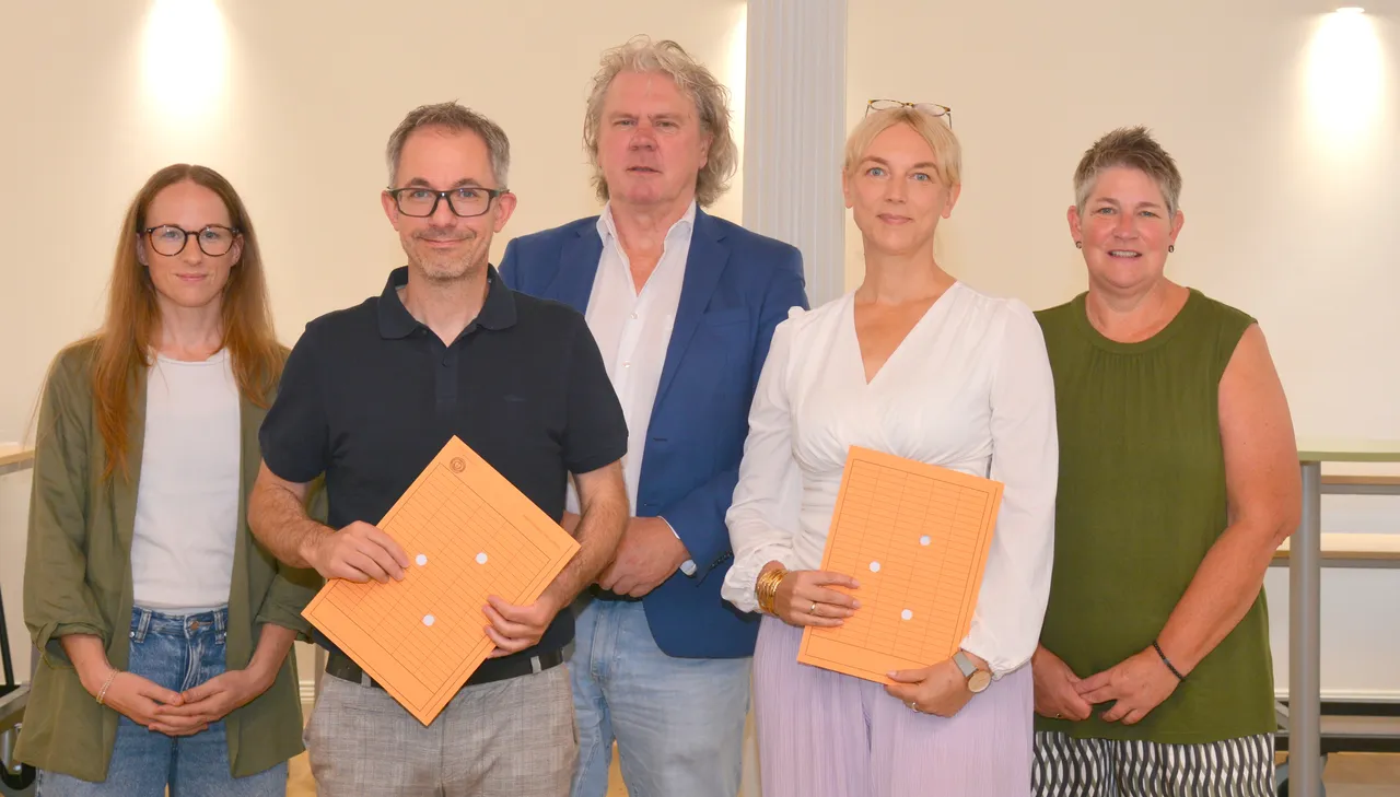 Jana Daube, Michael Tschöke, Matthias Reuber, Sabine Thiesbrummel und Esther Castelein stehen nebeneinander und halten orangefarbene Mappen.