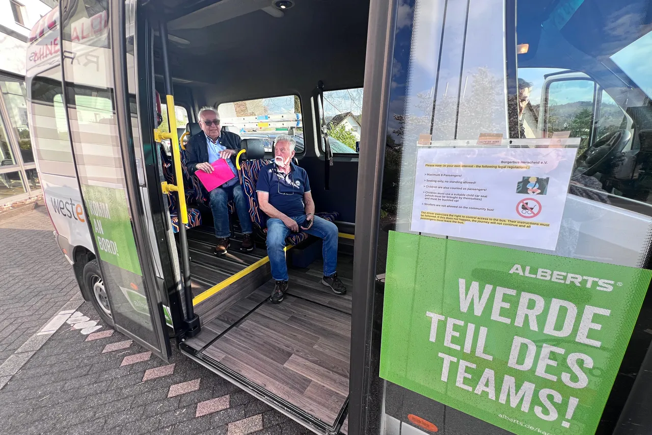 Ein Bürgerbus mit geöffneter Tür, in dem zwei Männer und ein Kind sitzen. Am Eingangsbereich befindet sich ein Werbebanner für die Rekrutierung von Teammitgliedern.