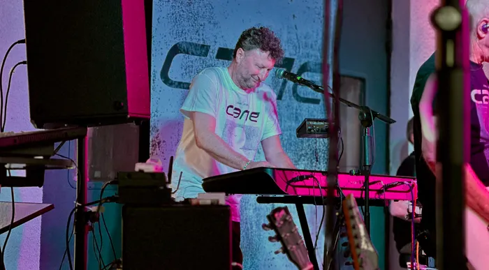 Ein Musiker der Band Cane spielt an einem Keyboard unter farbiger Bühnenbeleuchtung.