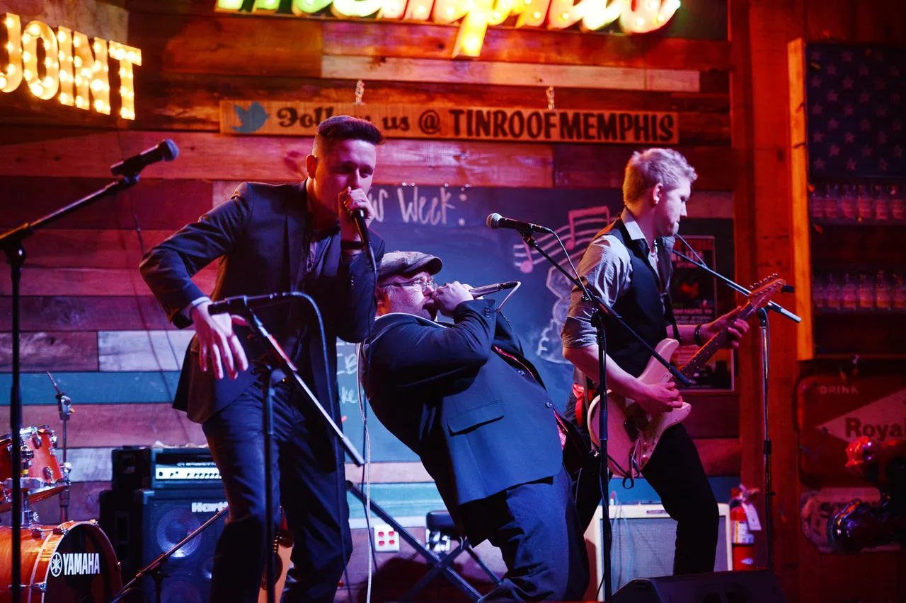 Die Band Chris Kramer & Beatbox ’n’ Blues tritt live auf einer Bühne mit Holzwänden und Neonreklamen auf.