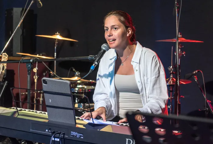 Eine Sängerin spielt am Keyboard und singt in ein Mikrofon während des Benefizkonzerts „Rock for Peace“.