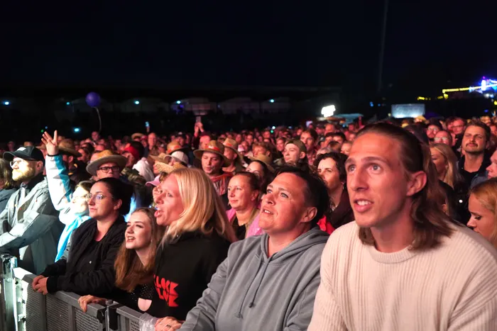 Eine Menschenmenge blickt bei einem nächtlichen Open-Air-Event gespannt nach vorne.