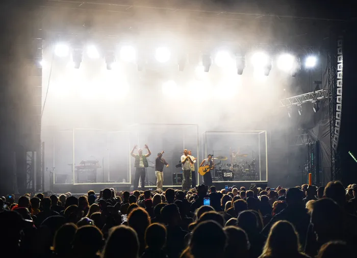 Die Band Clockclock performt auf einer hell erleuchteten, vernebelten Bühne vor einer großen Menschenmenge.