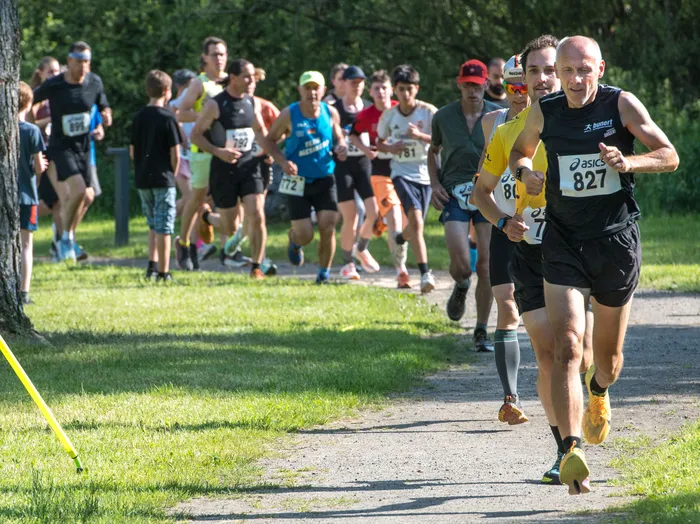 Läufer nehmen an einem Crosslauf in Oberbrügge teil. Ein Mann mit der Startnummer 827 führt das Feld an und blickt in die Kamera.