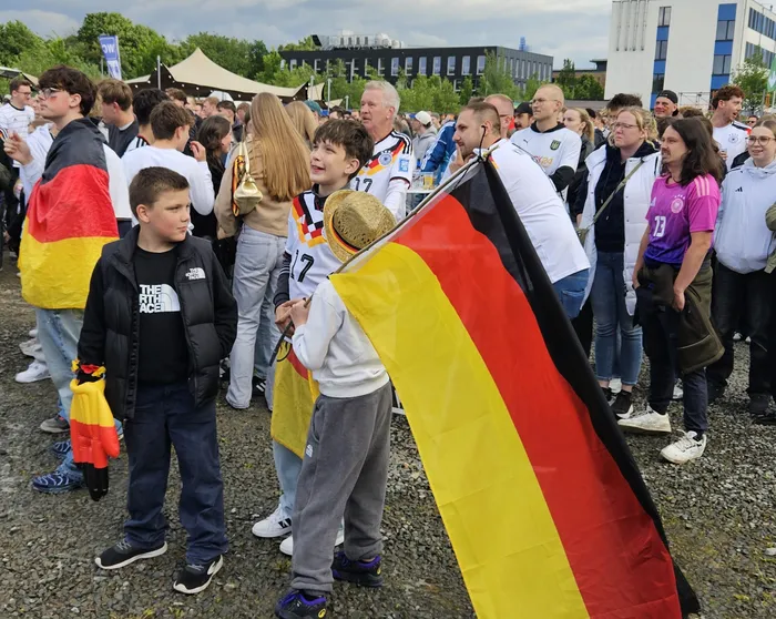 Jubelnde Fans mit Deutschlandflaggen und in Nationaltrikots feiern den Sieg der deutschen Nationalmannschaft gegen Curaçao bei einer XXL-WM-Party. Im Vordergrund ein Junge mit Strohhut.