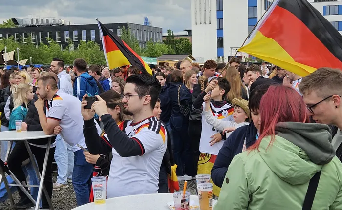 Eine Menschenmenge feiert mit Deutschlandflaggen den Sieg der deutschen Nationalmannschaft gegen Curaçao bei einer XXL-WM-Party. Viele Fans in Trikots und mit bemalten Gesichtern sind zu sehen.
