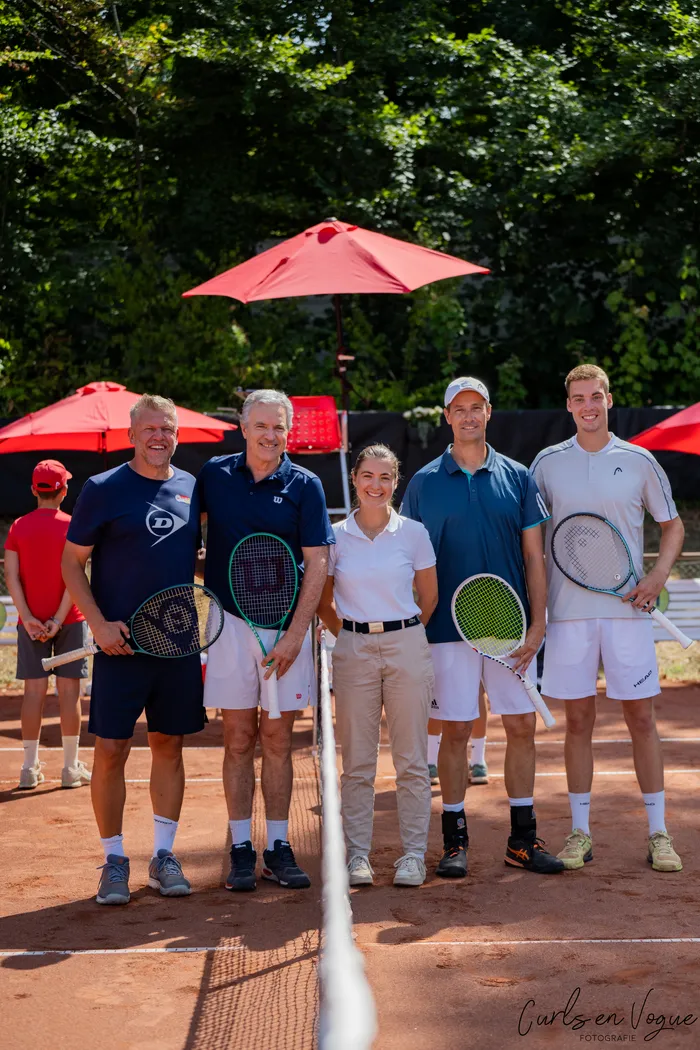 Fünf Personen mit Tennisschlägern posieren auf einem Sandplatz bei den Platzmann Open 2026.