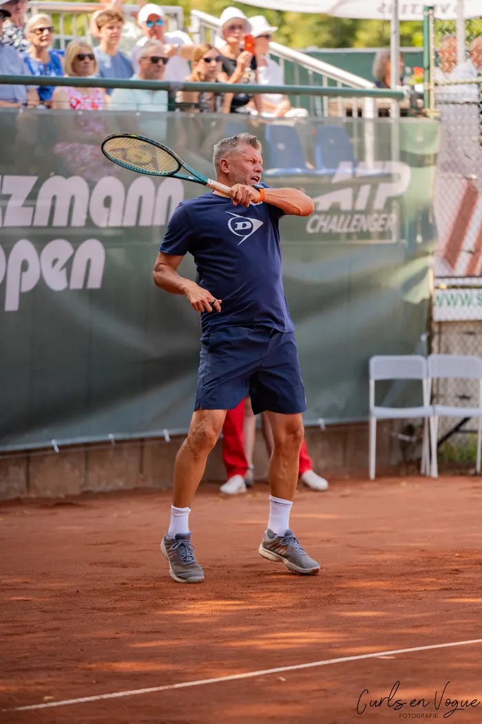 Ein Mann schwingt einen Tennisschläger auf einem Sandplatz während eines Show-Spiels bei den Platzmann Open 2026.