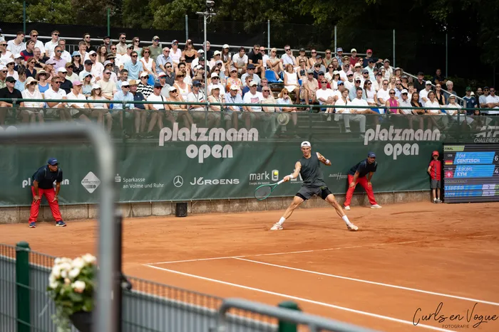 Tom Gentzsch spielt auf einem Sandplatz während der Platzmann Open vor einer Zuschauermenge.