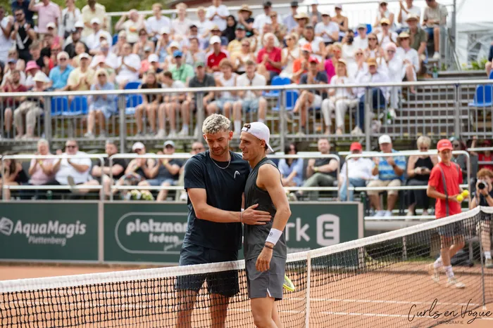 Tom Gentzsch umarmt einen anderen Spieler auf einem Tennisplatz vor einer Zuschauermenge.