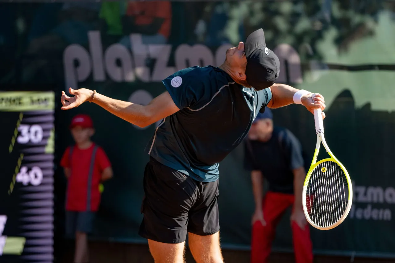 Tennisspieler Nikolai Barsukov mit ausgebreiteten Armen und Tennisschläger in der Hand auf dem Platz.