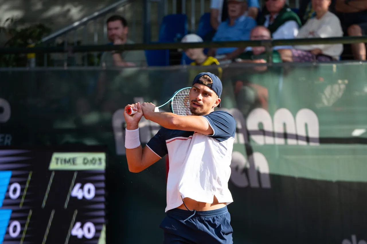 Marko Topo schwingt seinen Tennisschläger während eines Matches vor Zuschauern im Hintergrund.