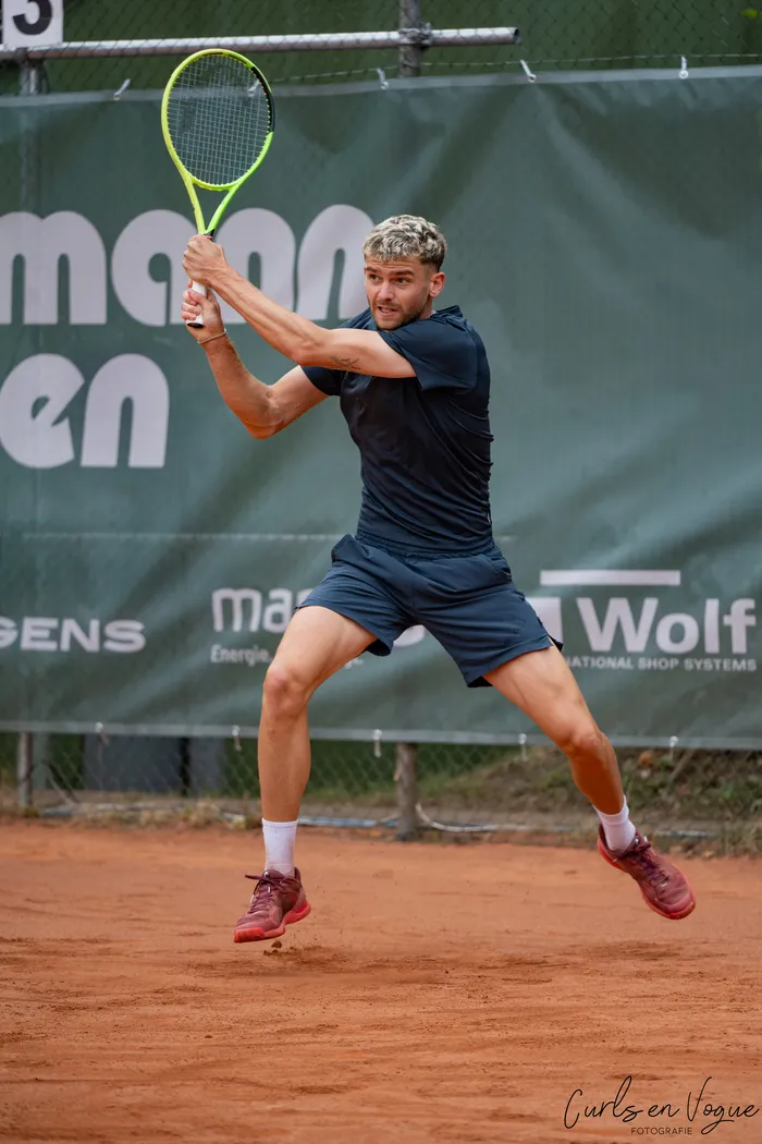 Jérôme Kym springt auf einem Sandplatz und hält einen gelben Tennisschläger bereit.