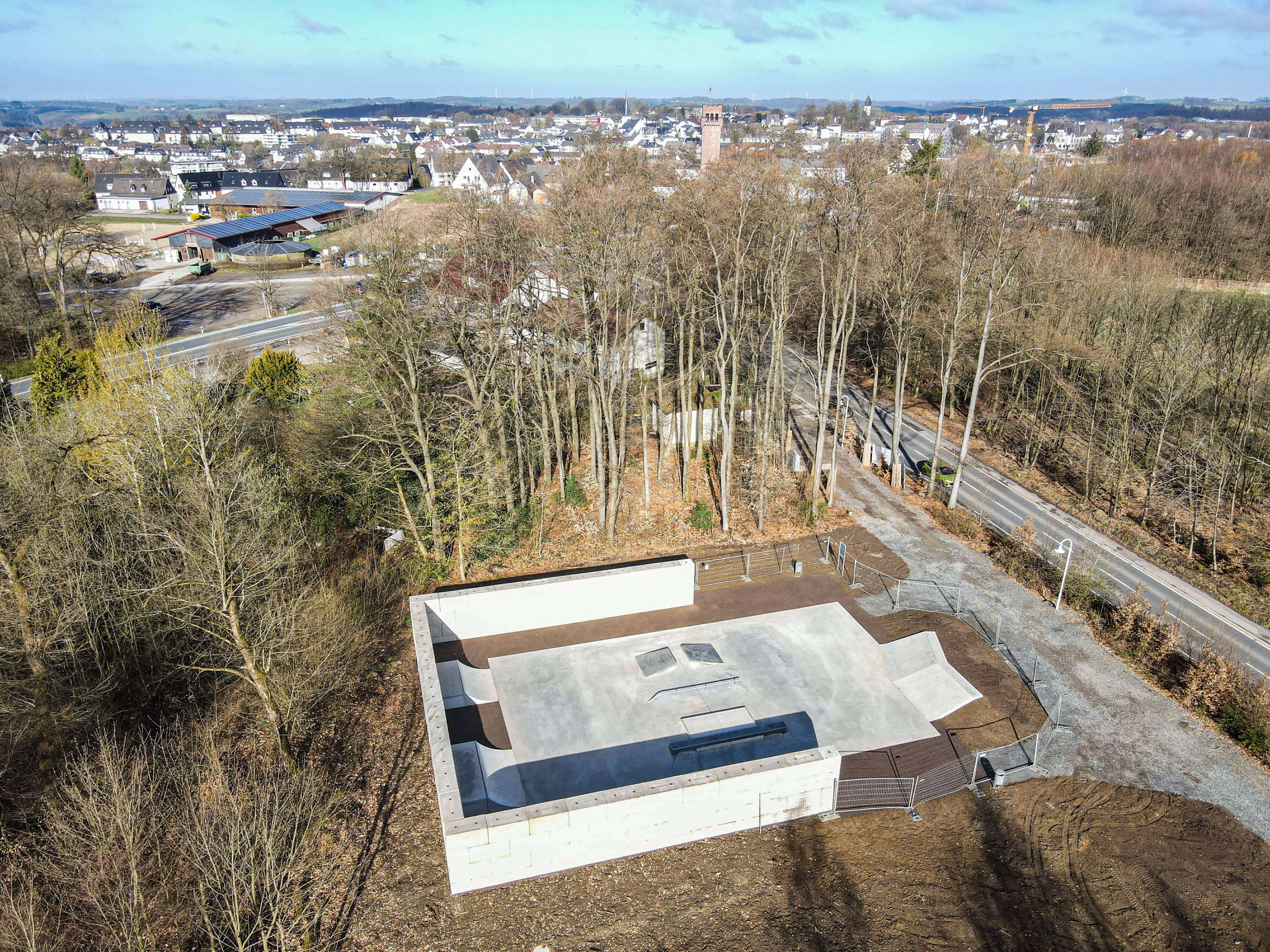 Luftaufnahme der neuen Skate- und Bikeanlage in Halver, umgeben von Bäumen und mit Blick auf die Stadt im Hintergrund.