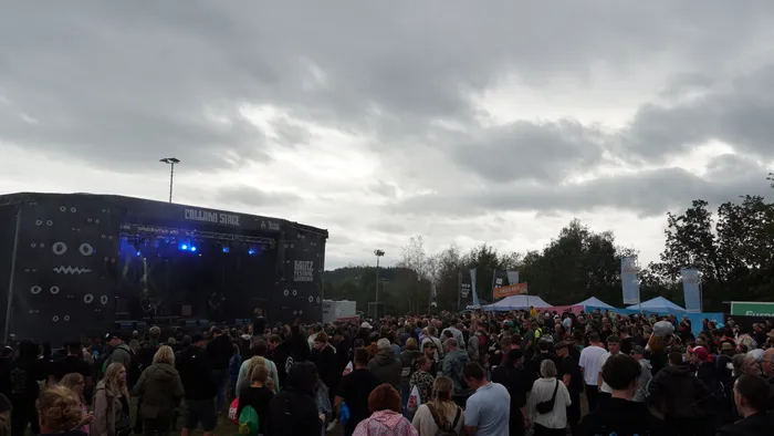Eine große Menschenmenge vor der Collabo Stage bei einem Festival unter einem bewölkten Himmel.