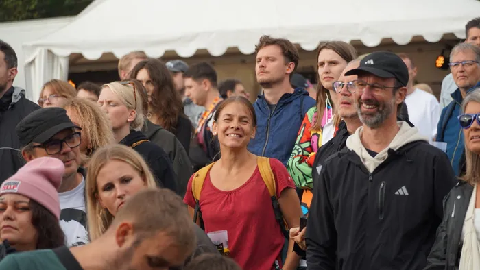 Eine Menschenmenge bei einem Festival, im Zentrum eine lächelnde Frau in einem roten T-Shirt.